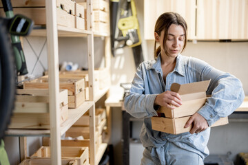 Young handywoman searching some working tools on a wooden shelves in the workshop. Concept of...