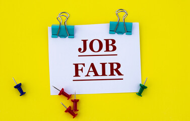JOB FAIR - Word on white paper with clips on yellow background with buttons and pencil