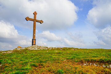 Wood cross on a green hill with beautiful clods