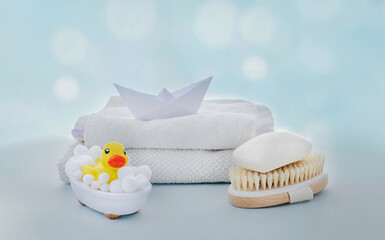 Yellow rubber ducky in small bath, natural brush and soap bar on light blue background. Baby bath, zero waste concept