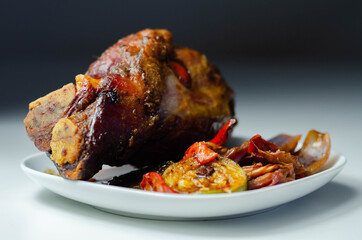 Bacon joint with bone served with grilled vegetables, red and yellow peppers, zucchini and red onion