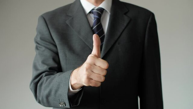 Close up of successful business man giving a thumbs up showing approval. Businessman, boss, and entrepreneur with positive gesture signaling OK, all right, and satisfaction.