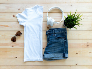 flat lay White tshirt mockup short jeans headphones and Sunglasses on brown wooden background. Template,