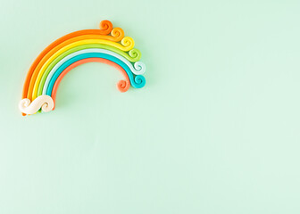 Rainbow in the corner of a light green background and a large space for a message.