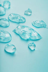 Drops of Gel with hyaluronic acid in the form of a smear of glossy texture on a cyan background.