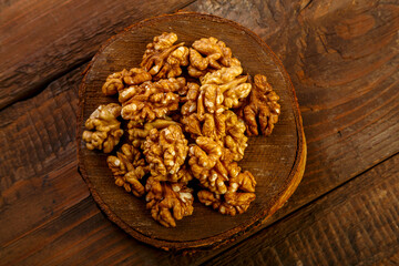 Walnuts are scattered on a round board on a wooden table.