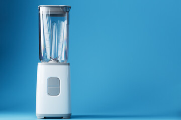 Electric blender with an empty cup on a blue background.