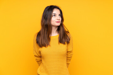 Obraz premium Young caucasian woman isolated on yellow background and looking up