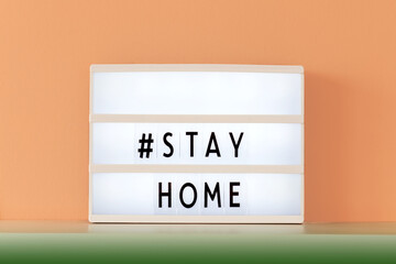 Stay home prevention message on white sign at home on a green shelf. Coronavirus text, people...