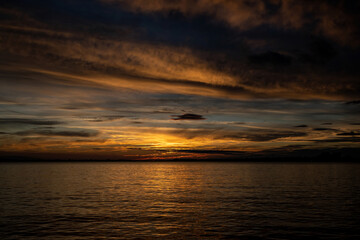 A sunset on the seashore. Soft sea ocean waves wash over golden sand background.