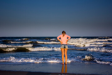 girl from the back on the shore of a wavy sea