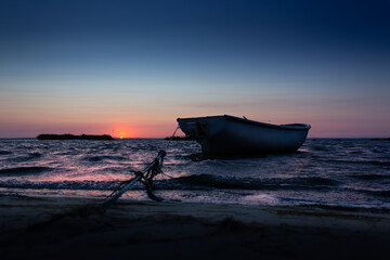 Sunset, sunrise on a wavy sea with boat