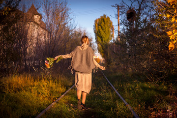 Girl with flowers in autumn on railway