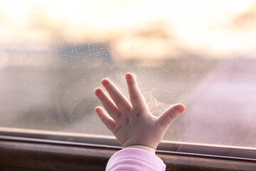 Child's hand leaning against the window. Frost outside the window