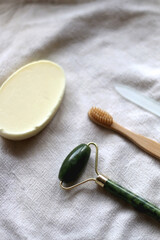 Jade face roller, wooden toothbrush, glass nail file and bar of soap. Sustainable body care products. Selective focus.