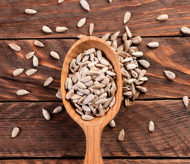 Sunflower seeds in a spoon on a wooden background