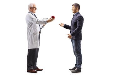 Full length profile shot of a doctor giving a red apple to a man