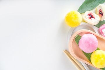 Traditional Japanese dessert mochi. Colorful mochi ice cream on a white table, whole and cut with berry, fruit filling