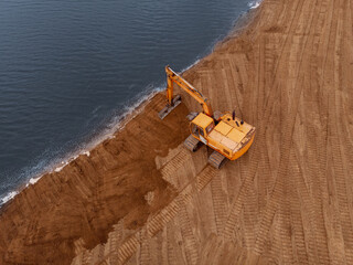 Excavator doing an earthwork on a shore.Aerial photography
