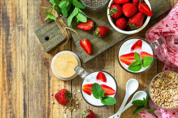 Fototapeta na wymiar Healthy eating. Breakfast concept. Homemade granola with strawberry, yogurt, chia seeds and fresh berries on a rustic table. Top view flat lay. Copy space.