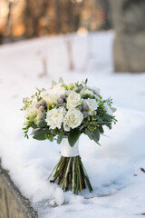 Beautiful bridal bouquet of white and pink flowers and greenery, decorated with long silk ribbon lies on a gray textural background.