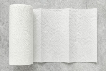 White roll of household paper towels on a gray background, shallow depth of sharpness
