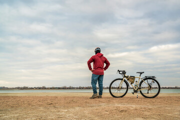 spring biking, touring or commuting - male cyclist with a bicycle on a lake beach, Boyd Lake State Park in northern Colorado