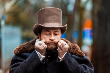 1900 style man wearing black hat and coat. Man in Dickens style.  - obrazy, fototapety, plakaty