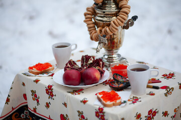 Tea drinking from a samovar in the winter outdoors in the forest. Russian traditions. Tea from a...