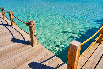 Naklejka premium Wooden sea pier with yellow ropes and beautiful clear water