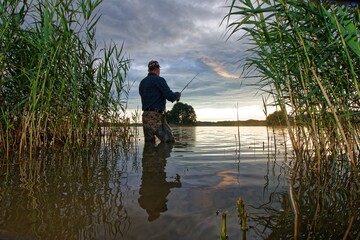 fisherman catching fish in the lake during cloudy day