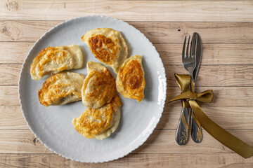 Roasted Varenyky, vareniki, pierogi, pyrohy or dumplings, filled with cheese and potatoes, on a grey gray plate