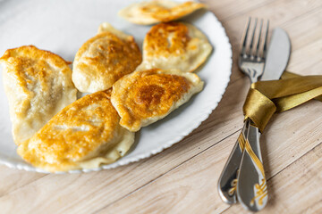 Roasted Varenyky, vareniki, pierogi, pyrohy or dumplings, filled with cheese and potatoes, on a grey gray plate