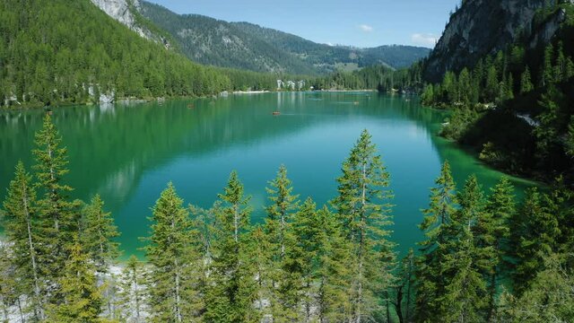 Aerial footage over lake Braies, Pragser Wildsee and mountains, in the background, on a sunny bright summer day, in Dolomites, Italy