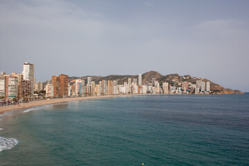 Fototapeta na wymiar View of the Mediterranean sea without waves, the Levante beach and the skyline of Benidorm on the Alicante coast with the mountains in the background.