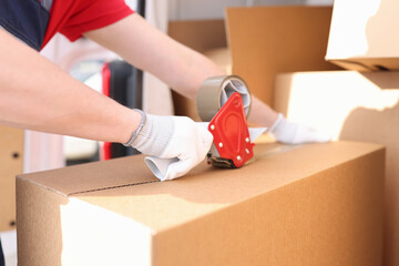 Man seals box with adhesive tape dispenser