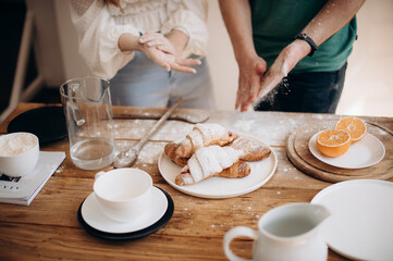 a girl and a guy are preparing croissants with a filling for breakfast close-up