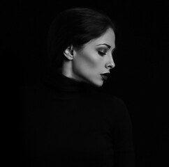 Sexy woman with bright evening makeup, red lipstick brown brow posing isolated on dark black background. Closeup portrait in deep low key light shadows. Art.