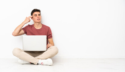 Teenager man sitting on the flor with his laptop with problems making suicide gesture