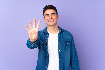 Teenager caucasian  handsome man isolated on purple background happy and counting four with fingers