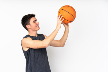 Handsome young basketball player man over isolated wall playing basketball