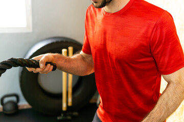 Young athlete exercising with ropes in gym