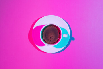 Cup of coffee on pink background. Double colorful shadows