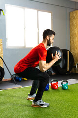 Obraz premium Young athlete exercising in the gym with a ball