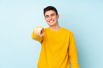 Teenager caucasian handsome man isolated on purple background points finger at you with a confident expression