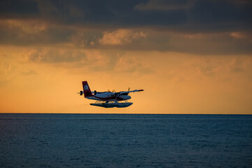 Take-off of a red seaplane on the maldivian lagoon at sunset. beautiful dramatic sky