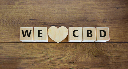 We love CBD symbol. Wooden cubes and wooden heart with words 'I love CBD'. Beautiful wooden background, copy space. We love CBD concept.