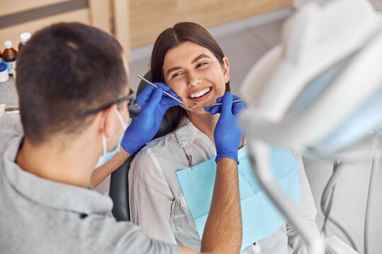 Cheerful positive dentist and client in dentistry. They look at each other and smile. Female client sit in chair