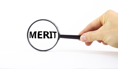 Merit symbol. Magnifying glass with word merit on a beautiful white background. Businessman hand....