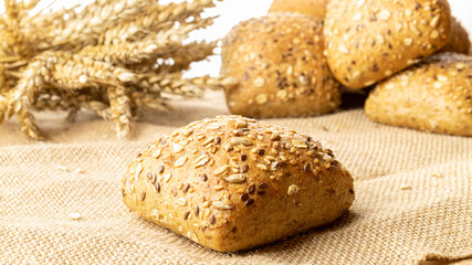 Bakery products. Rye bakery with crusty loaves and crumbs. Fresh loaf of rustic traditional bread with wheat grain ear or spike plant on natural cotton background. Concept - Cooking at Home.